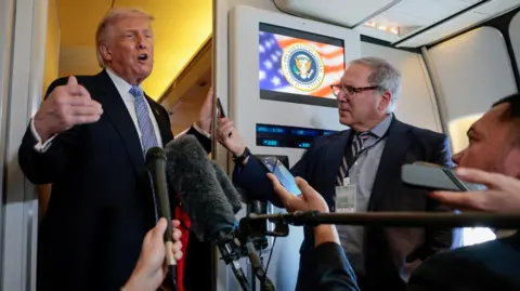 Reuters Donald Trump (L) stands on Air Force One speaking and gesturing to reporters holding microphones and phones