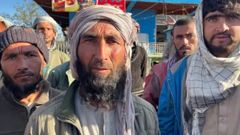 Imogen Anderson/BBC Juma Khan stands in the middle of a group of labourers who say they have all been struggling to find work 