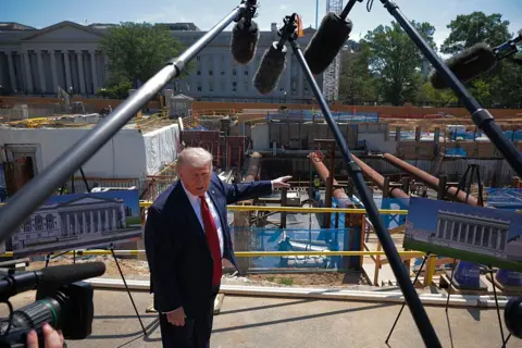 Getty Images Trump speaking to to reporters next to the ballroom building site inside the White House grounds