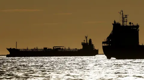 EPA Silhouettes of two tankers on silver ocean water against a golden sunset
