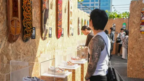 BBC/Hosu Lee A man admiring the tattoo designs on display 