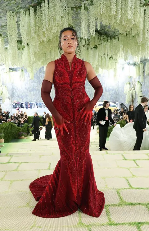 Getty Images Naomi Osaka reveals a red dress underneath her coat.