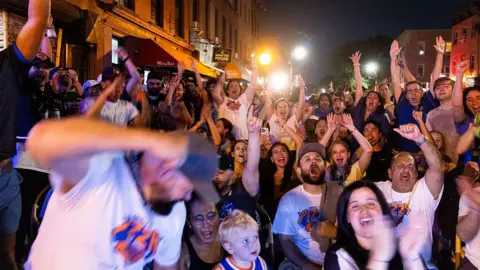 Corbis via Getty Images Dozens of fans cheering and watching a basketball game in the street