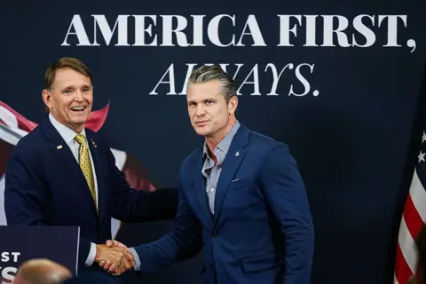 Getty Images Defence Secretary Pete Hegseth shakes hands with Gallrein at a campaign event in Kentucky on Monday. They are standing in front of a sign that reads "America First, Always". 