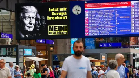 Reuters A poster shines out over a railway station as people walk underneath