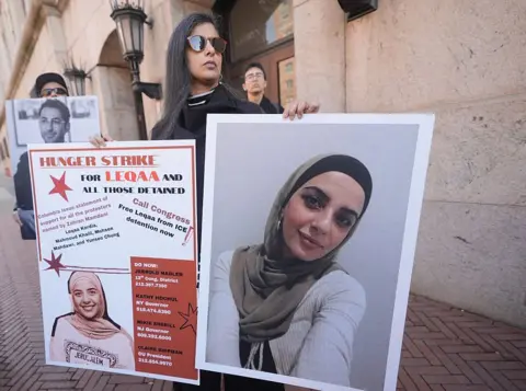 Getty Images A woman holds up posters showing pictures of Leqaa Kordia as Columbia students, professors and supporters gather in front of the university.