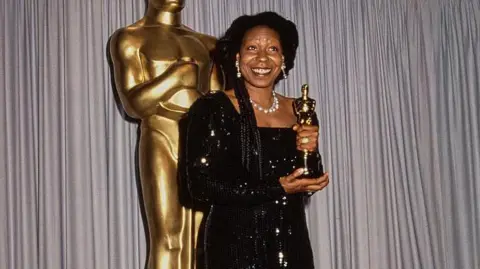 Getty Images American actor and comedian Whoopi Goldberg, wearing a sparkling black full-length evening gown, in the 63rd Academy Awards press room at the Shrine Auditorium in Los Angeles, California, 25 March 1991. 