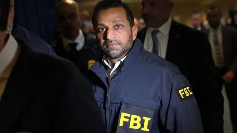 Getty Images FBI Director Kash Patel stands in a crowd while wearing a dark utility jacket emblasoned with FBI on the front and arm.