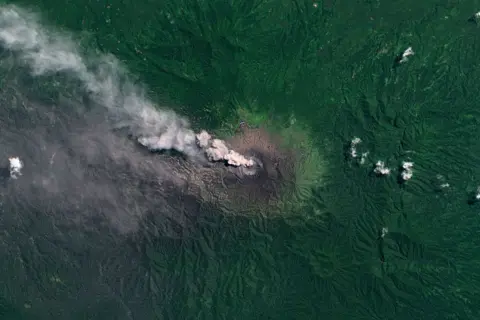 Getty Images Satellite image of Mount Dukono showing plumes of smoke coming out of the volcano's crater, surrounded by dense green vegetation