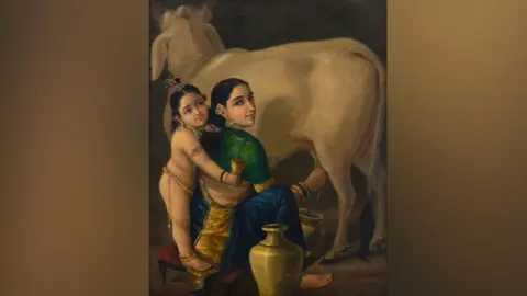 Saffronart A woman wearing a green blouse and a blue saree is seen milking a cow in the oil portrait. A child, who is Hindu deity Krishna, is seen standing next to her wearing jewellery. 