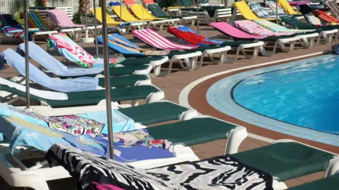 Getty Images Towels on sunbeds around a swimming pool.