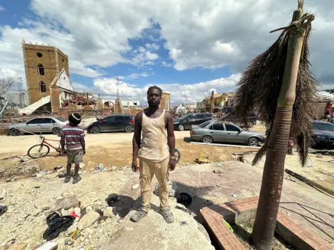 Brandon Drenon / BBC Demar Walker is seen standing before debris and cars