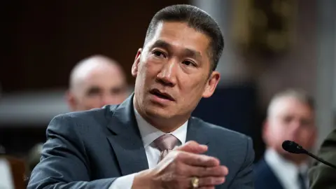 CQ-Roll Call, Inc via Getty Images Hung Cao in a suit seated in front of a microphone. He is gesturing with his hands.