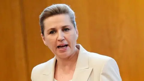 EPA Mette Frederiksen speaking in parliament, wearing a beige jacket over a white top