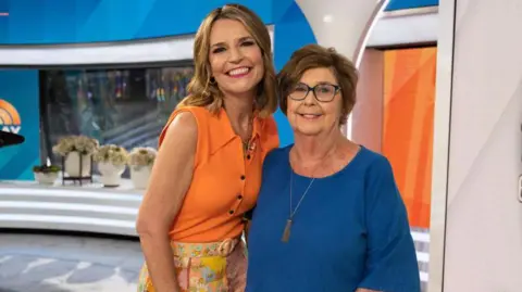 NBC via Getty Images Savannah Guthrie and her mother Nancy smiling with their arms around each other in a TV news studio