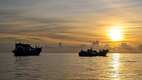 AFP via Getty Images A boat carrying Rohingya refugees (left) sails ashore off the coast of Labuhan Haji in Southern Aceh province in 2024