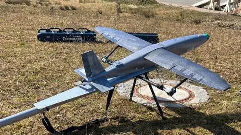 Department of Defense A fixed-wing drone about 1m in wingspan and length is on a metal launch platform