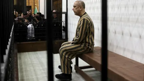 Reuters Atef Najib, former head of Political Security in Deraa under ousted president Bashar al-Assad, attends a trial session at the Palace of Justice, in Damascus, Syria (26 April 2026)