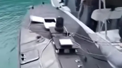 Lefkadatika Nea A screenshot showing the discovered naval drone (left) is being towered by a Greek coastguard boat to the port of Vasiliki on the island of Lefkada in the Ionian Sea