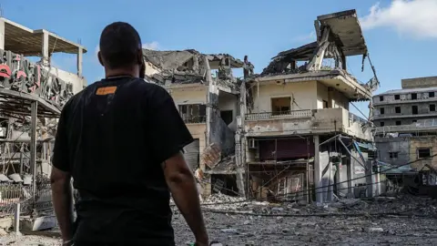 Abbas FAKIH / AFP via Getty Images A man stands in front of a heavily damaged building in the centre of Nabatieh on June 15, 2026. 