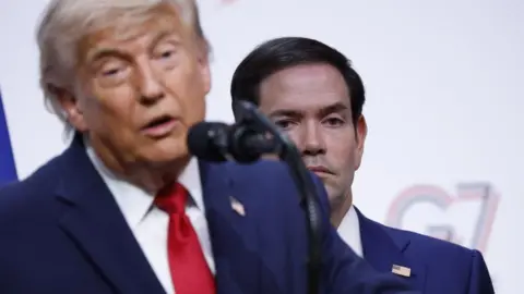 EPA US Secretary of State Marco Rubio (R) listens as President Donald Trump speaks at the G7 summit in France on 17 June 2026