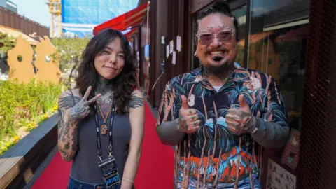 BBC/ Hosu Lee Kali (left) and Gil Taeho (right). Both have tattoos over the arms and are smiling at the camera
