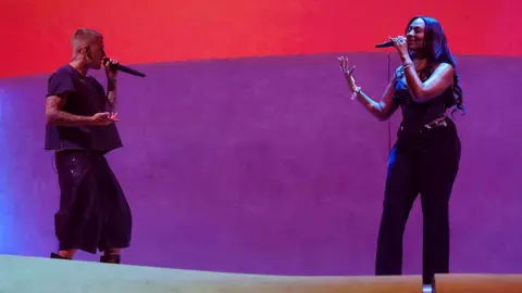 Getty Images Justin Bieber and Tems pictured on stage at Coachella, in front of a red and purple background.