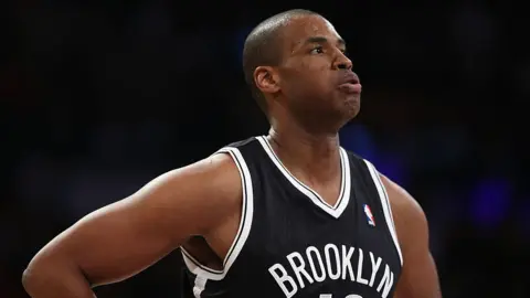 Getty Images Jason Collins is seen playing for the Brooklyn Nets. He is wearing a black NBA jersey and is exhaling