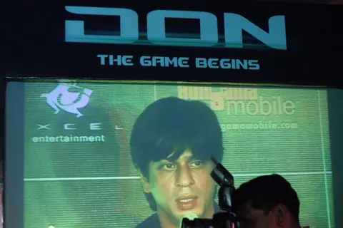 AFP via Getty Images A member of the media stands in front of a big screen as he photographs Indian filmstar Shahrukh Khan at the launch of a mobile game based on his new film 'DON' in Mumbai, 27 October 2006. 