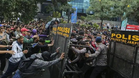 Getty Images Students protesters in Indonesia try to push through a police barricade