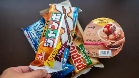 AFP via Getty Images A stack of packaged Japanese ice cream, a hand holding one pack on top of three others.