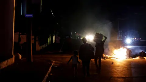 Reuters Three children stand before a burning pile of rubbish in the middle of a road in Havana, the street is completely unlit barring distant car headlights. 