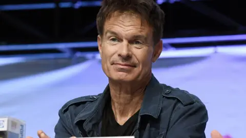 Getty Images Patrick Muldoon at Comic Con last year, he is wearing a navy combat-style jacket and a black T-shirt