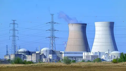 Getty Images Cooling towers of the Doel Nuclear Power Station, nuclear power plant and high-voltage electricity pylons in the Antwerp harbour, Flanders, Belgium
