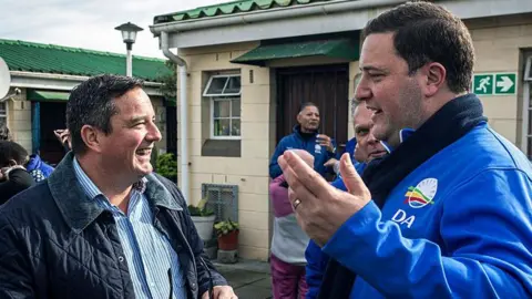 Getty Images John Steenhuisen is seen laughing with his successor Geordin Hill-Lewis at an event