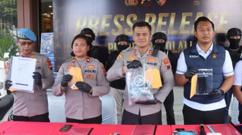 Boyolali Police Investigators in police unforms pose with bags of evidence at a media briefing