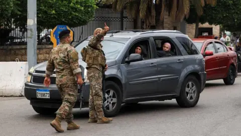 Reuters soldiers direct a car with women inside
