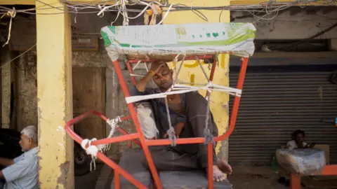 Reuters A man sleeps in his cycle rickshaw outside a market area on a hot summer day in New Delhi, India April 29, 2026.
