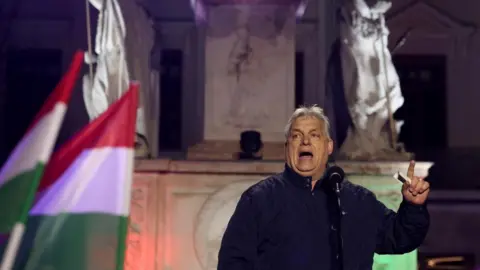 Reuters A man speaks at a microphone in front of statues