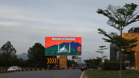 REUTERS/Akhtar Soomro A broad sky photo with a highway below centers on an orange and blue billboard that says "Welcome to Islamabad".