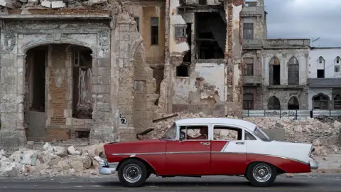 Getty Images An old car drives past debris from a demolished house occupying part of the seaside promenade in the Centro Habana neighbourhood in Havana on 9 June , 2026