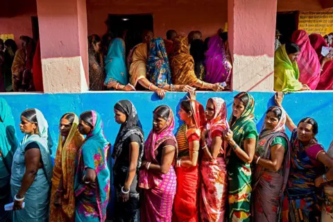 AFP Women voters stand in queues to cast their ballots at a polling station during the first phase of voting for assembly elections on November 6, 2025, at the Raghopur constituency in the Vaishali district of the Indian state of Bihar.