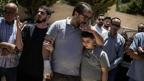 AFP via Getty Images Fahd Abou Haikal, a Palestinian man comforts his elder son Kinan Abou Haikal after burying his seven-month-old baby Sam Fahd Abou Haikal, in Hebron, in the occupied West Bank 