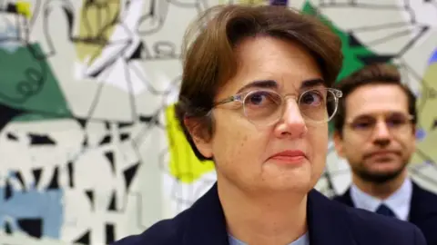 Reuters Head and shoulders picture of Laurence des Cars wearing glasses and standing in front of an artwork which is part visible behind her