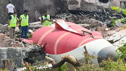 Hindustan Times via Getty Images Photo from Air India plane crash site, taken on June 13, 2025 in Ahmedabad. The tail of the plane is visible with men inspecting it.