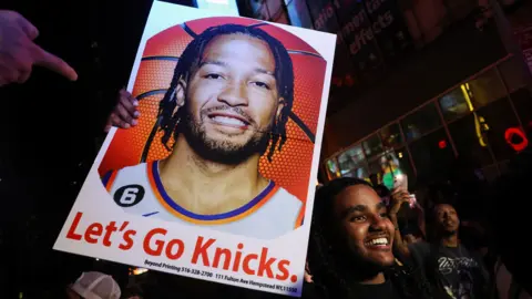 REUTERS/Shannon Stapleton A man holds a poster of New York Knicks point guard Jalen Brunson, as fans gather in Times Square. 
