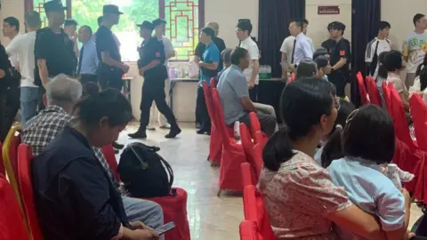 Early Rain Covenant Church Some congregants sitting on chairs while others, mostly men, stand in line to be escorted away by police officers