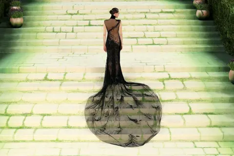 Getty Images Cara Delevingne is seen standing on the Met staircase, her back to the camera. Her Ralph Lauren has dramatic sheer details and a long train in the back.