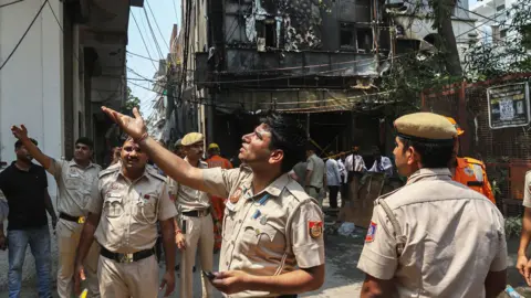 EPA Firefighters stand at the site of a hotel fire in New Delhi , India
