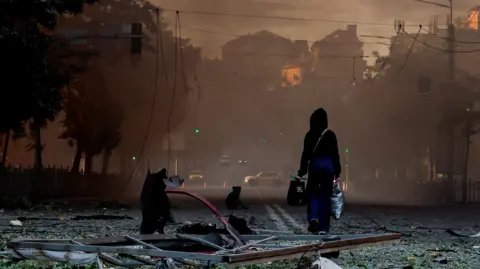 Reuters A person walks on a debris-scattered street in the aftermath of an overnight Russian missile and drone strike on Kyiv, Ukraine 24 May 2026.